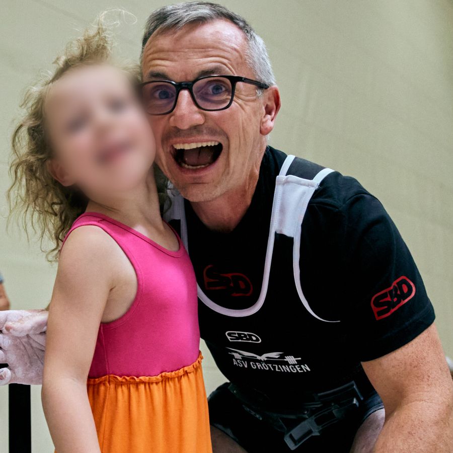 David Menner lacht beim Wettkampf, neben ihm seine Tochter mit unkenntlich gemachtem Gesicht